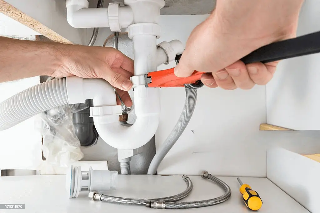 A picture about how to install a sink drain pipe in which a plumber is fixing a drain pipe 